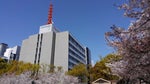 大阪科学技術センタービルの屋上塔屋に赤色の鉄塔、西側壁面には“大阪科学技術館”と館のキャラクター“テクノくん”の看板が目印。ビル西側に隣接する靭公園（うつぼこうえん）では桜の花が満開。【2019年4月17日撮影】）。
※シンボル的な屋上塔屋の鉄塔(赤色)は平成とともに終わりを遂げました。